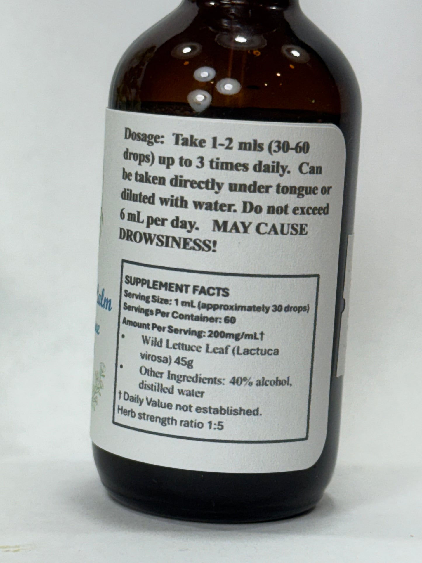 label close-up of Wild Lettuce Herbal Tincture drops in a glass dropper, offering natural sleep aid and relaxation